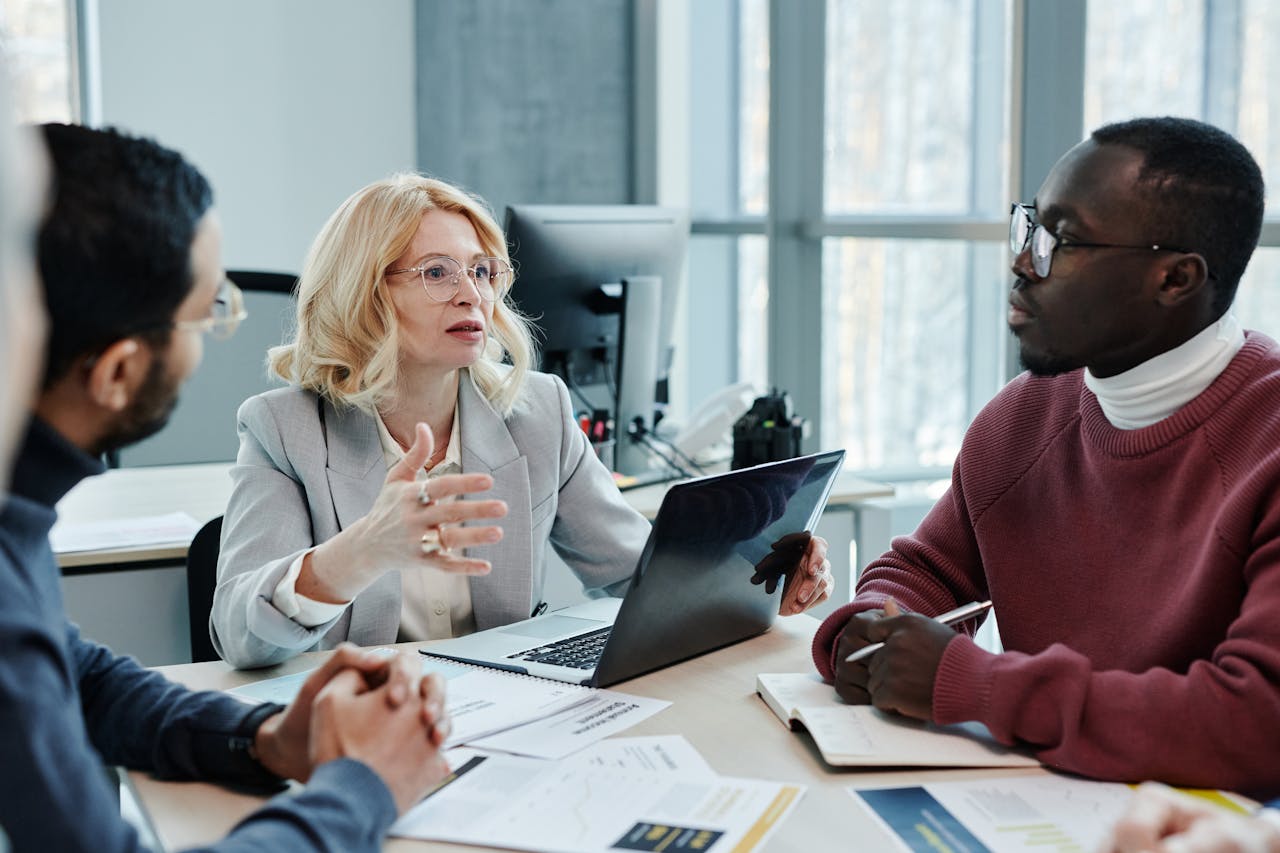 Home Business professionals discussing strategy around a table with a laptop in an office setting.